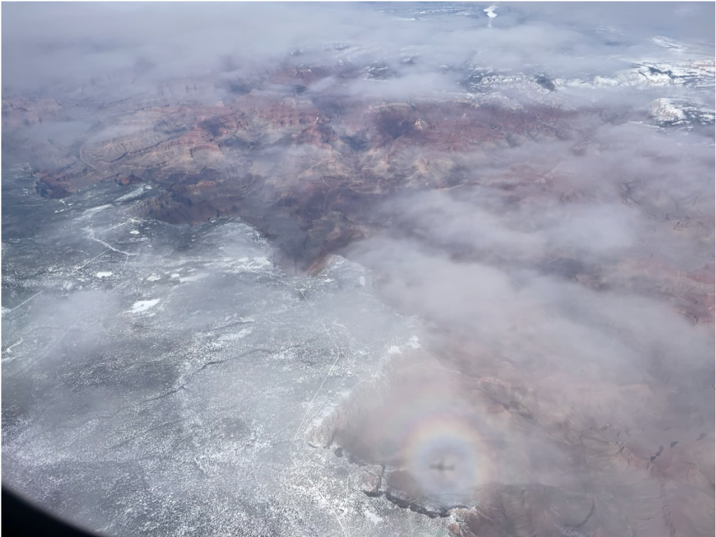 The shadow of the plane is surrounded by a circular ring of colors, in an aerial view of the Grand Canyon.