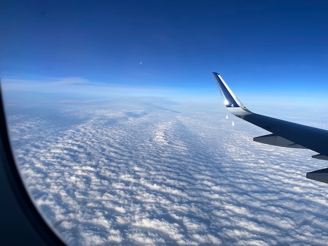 An aerial view shows the tops of an array of clouds with dramatic shadows.