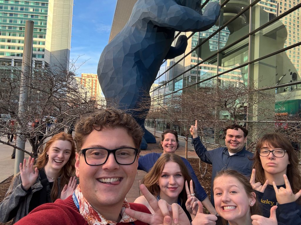 Several people pose with a large blue bear statue